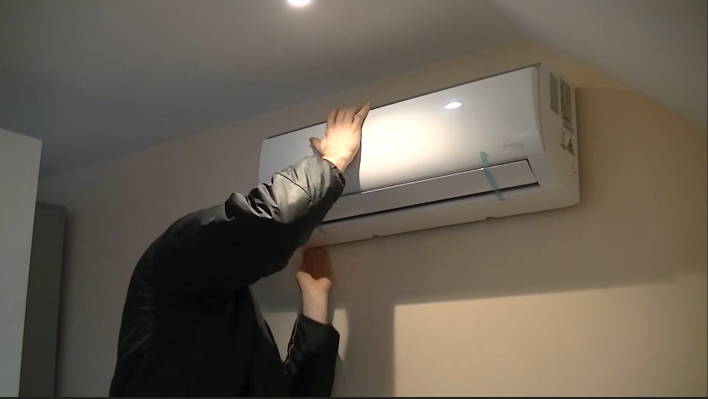 Technician checking a wall AC unit for resale in Qatar